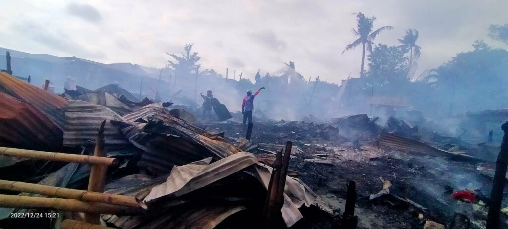 A fire volunteer talking to one of the residents who try to collect a metal pole that remains to be useful from the ashes of his house.  Photo by Aaron Lloyd Balala Refoyo